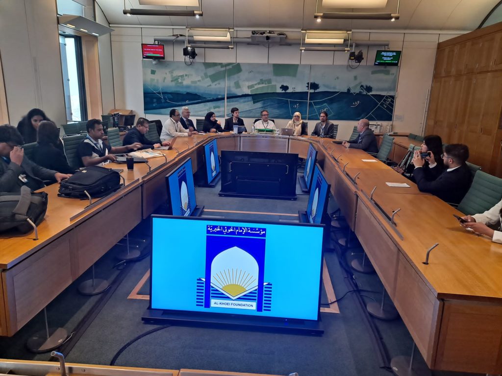 An event in a UK parliament Committee Room organised by Al Khoei Foundation, whose logo appears on screens around the room