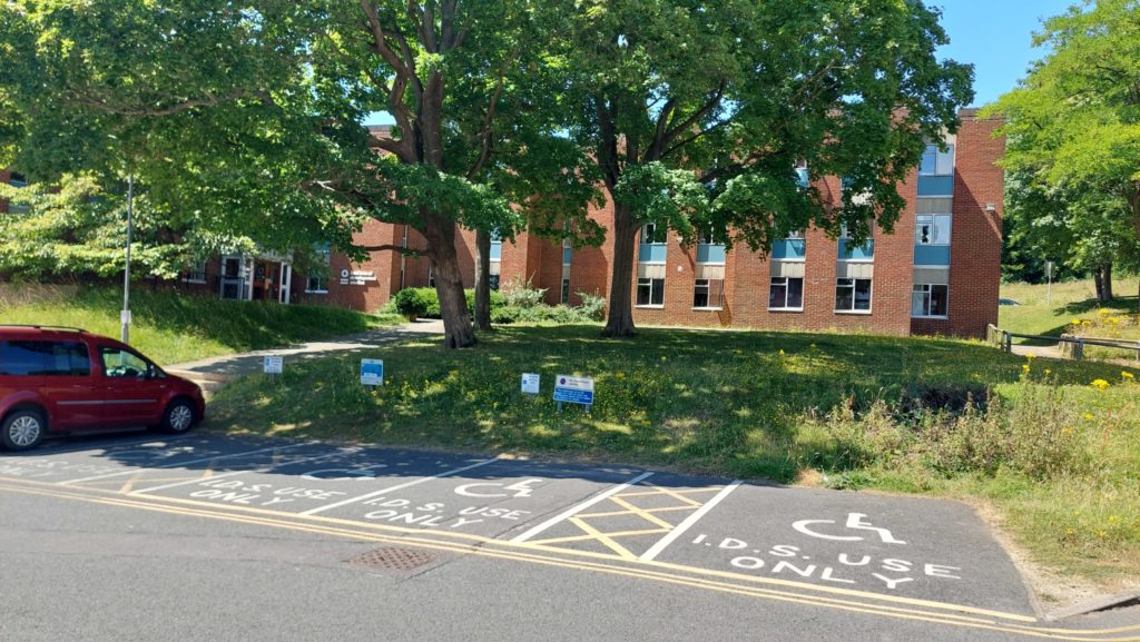 Accessible parking bays at the front of the IDS building. There are four free bays in the photo and one with a red car within the end bay.