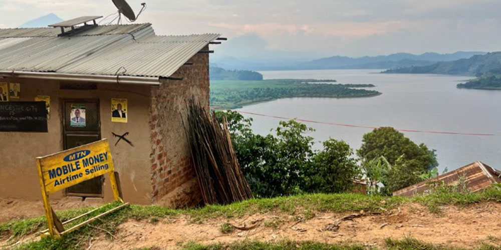 A small house with a satellite dish on top overlooks a bay in Ghana. A sign in the bottom left near the house reads: MTN. Mobile Money: Airtime selling.