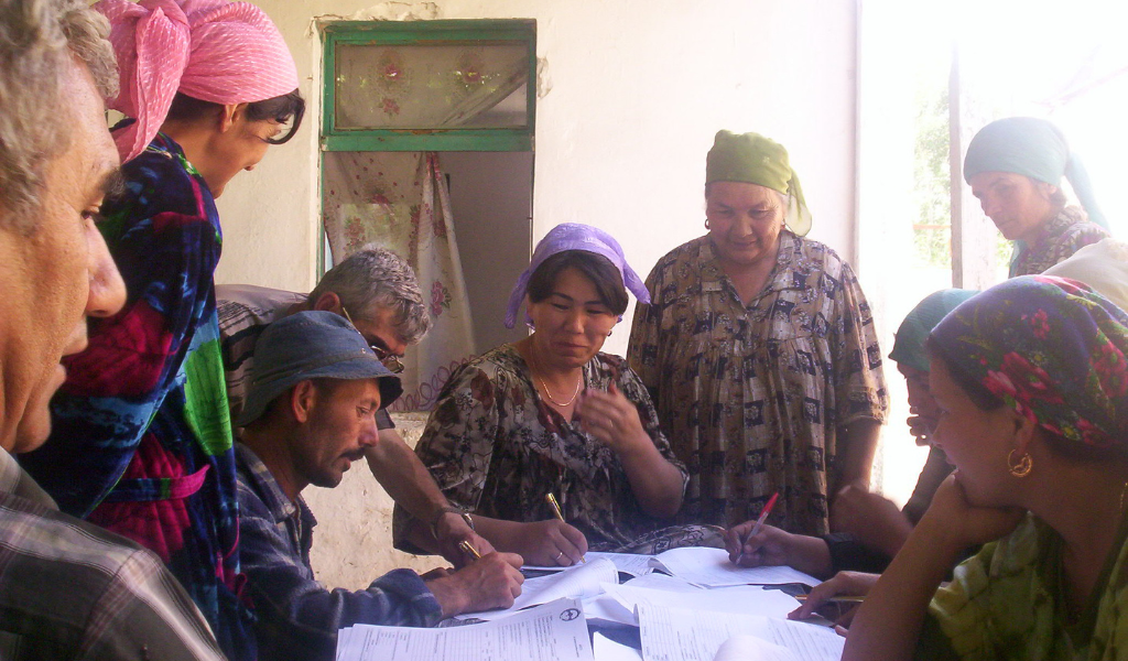 8 People are pictured around a table covered in documents.