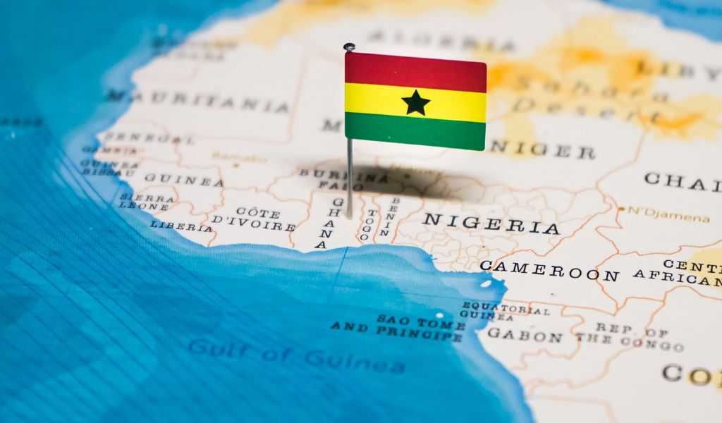 A small flag of Ghana pinned into the country of Ghana on a map of Africa.